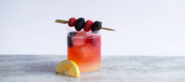 sunset orange tequilla tea cocktail with fresh berries and lemon